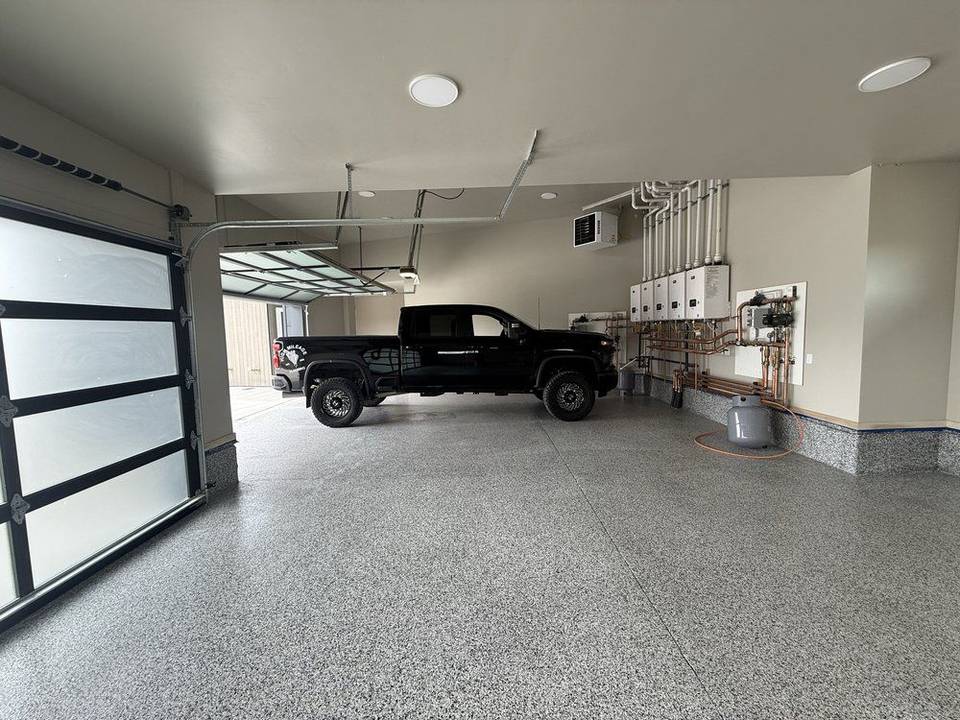 Gray flake polyaspartic garage floor with a black pickup parked inside